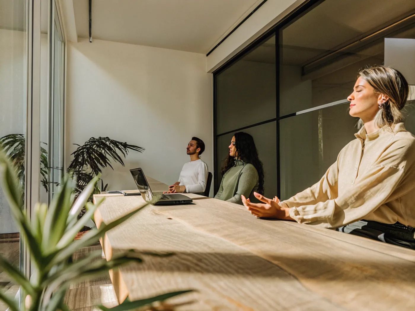 Uma pausa de mindfulness numa sala de reuniões: cinco pessoas sentadas de olhos fechados e uma instrutora de pé ao lado